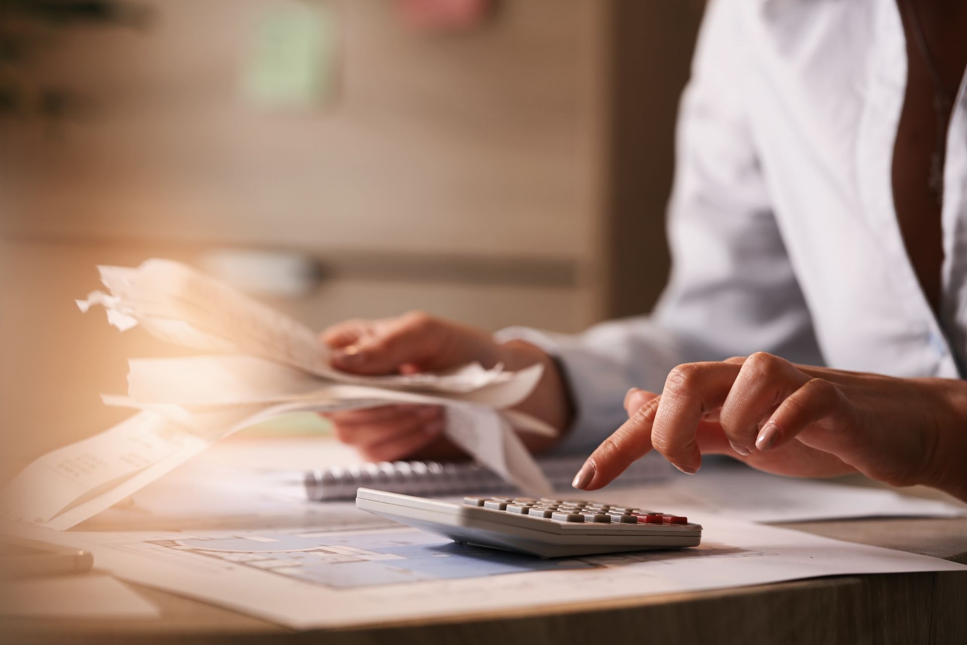 Person calculating expenses with a calculator and receipts.