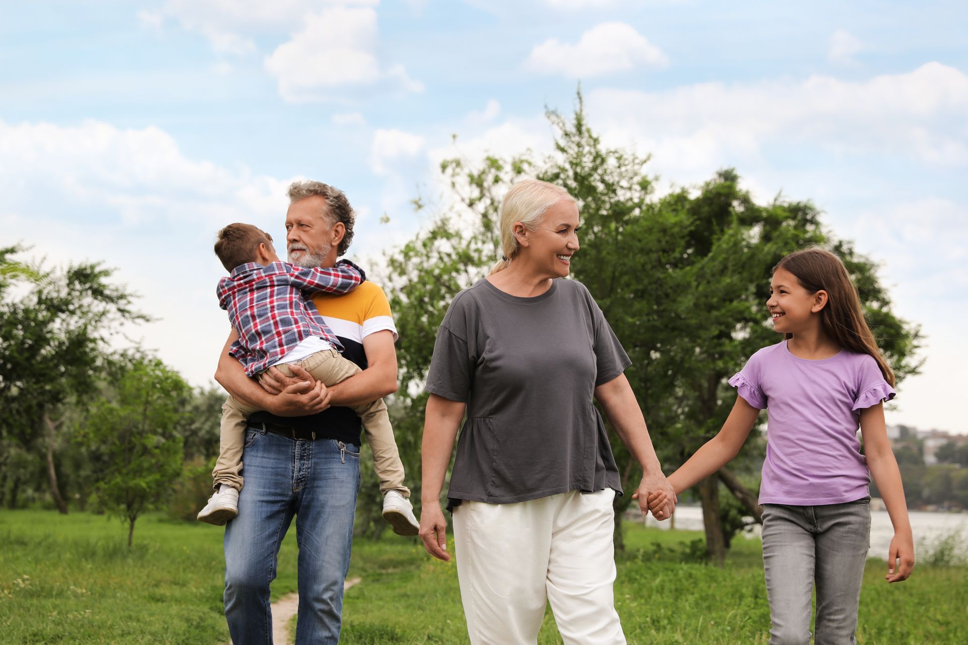 Two adults and two children walking together in a park.