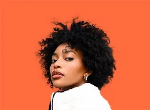 Young Black woman with curly hair against a bright orange background; looking towards the camera.
