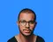 Man with glasses, short hair, and a goatee against a blue background.