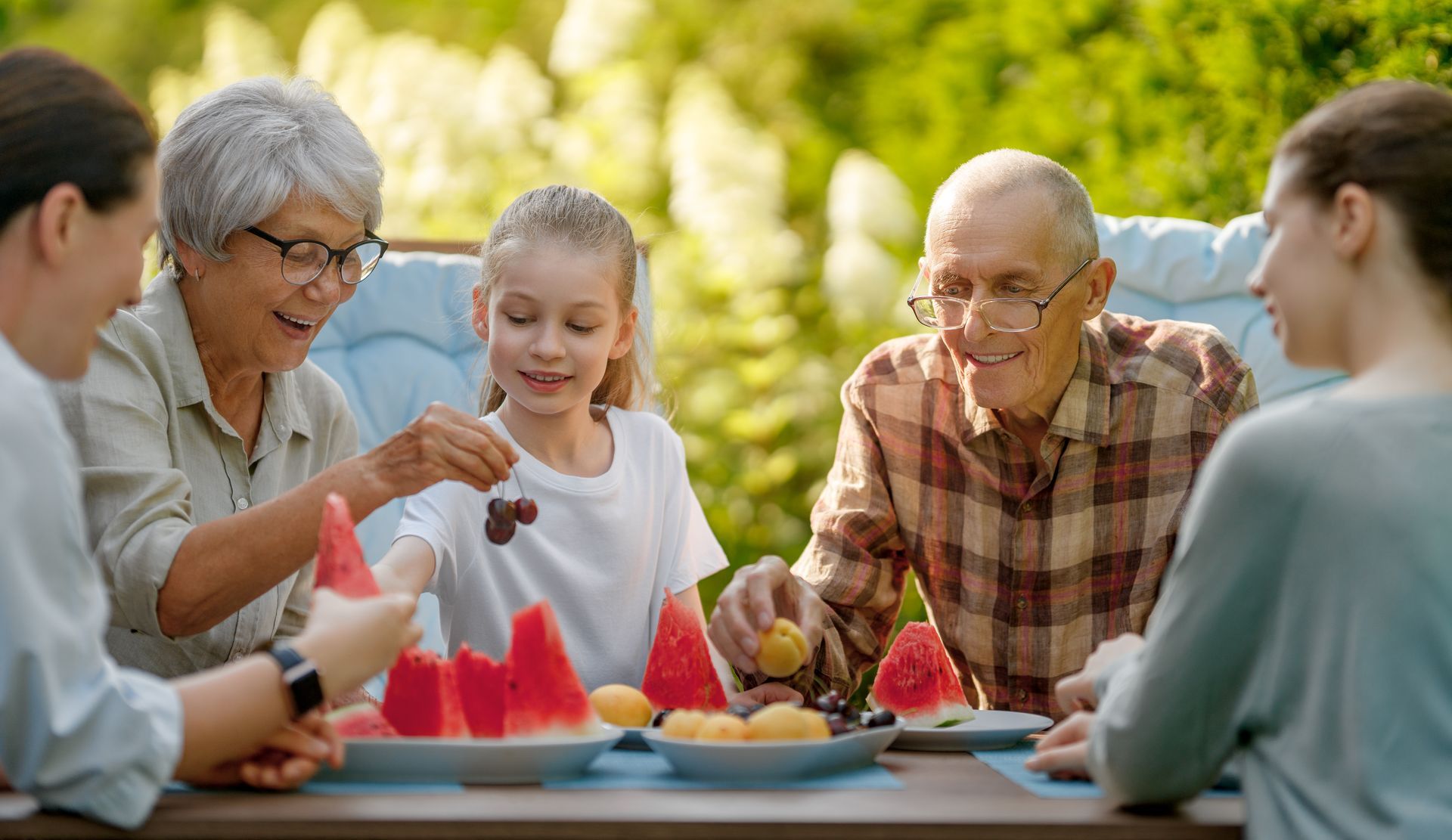 Family sharing fruit outdoors; smiles, summer day.