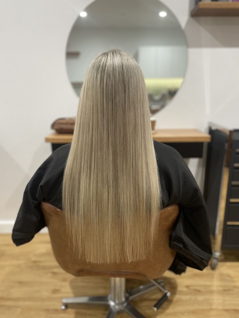 Person with long, straight, blonde hair sits in salon chair with mirror in background — Clippers Hair Salon in Taree, NSW