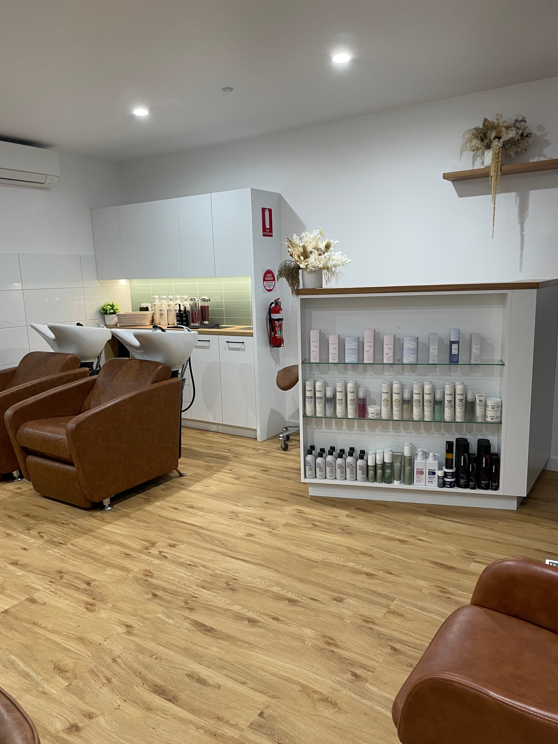 Hair salon interior with brown chairs, white shelving, and wooden floors — Clippers Hair Salon in Taree, NSW