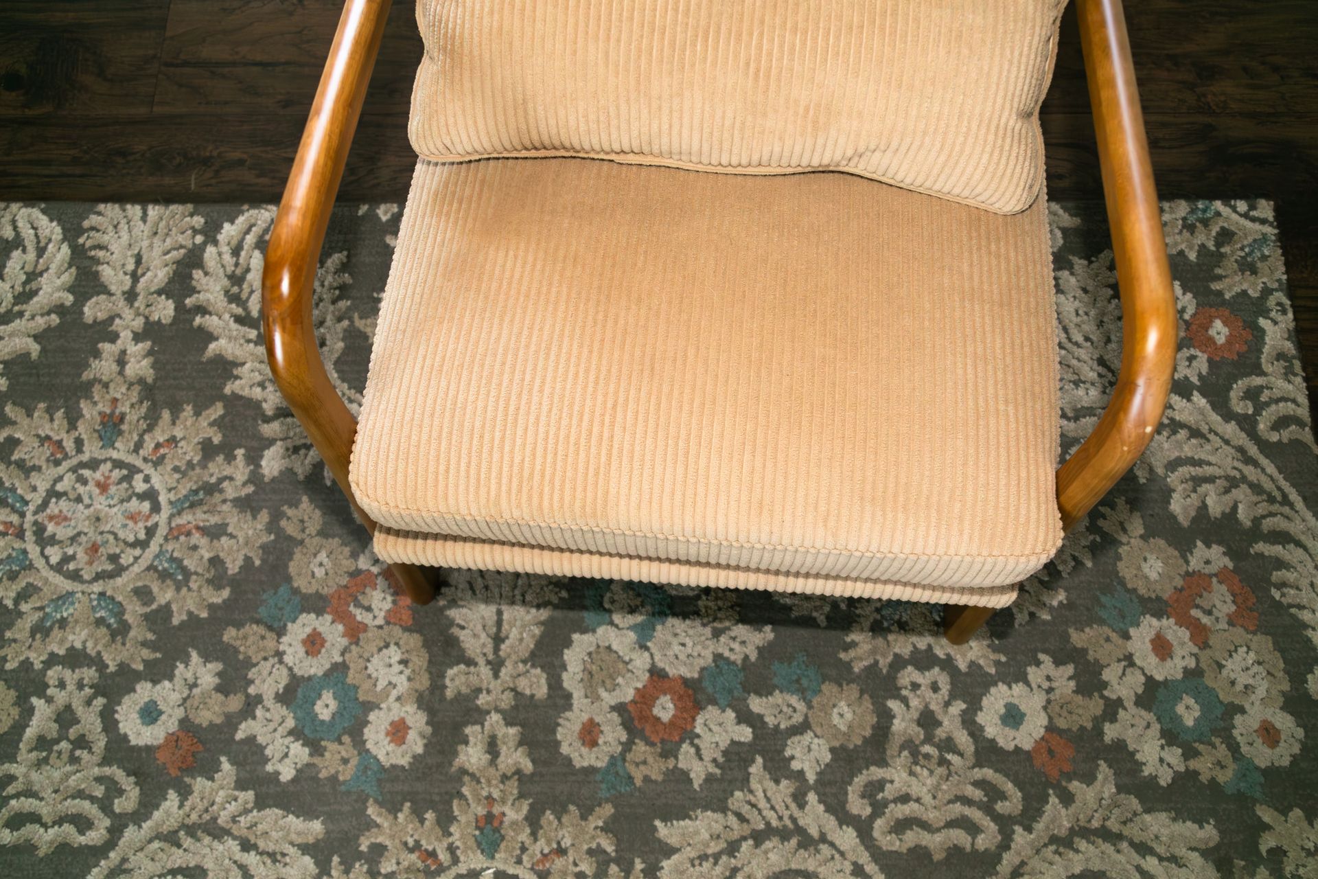 Beige cushioned chair on a patterned carpet