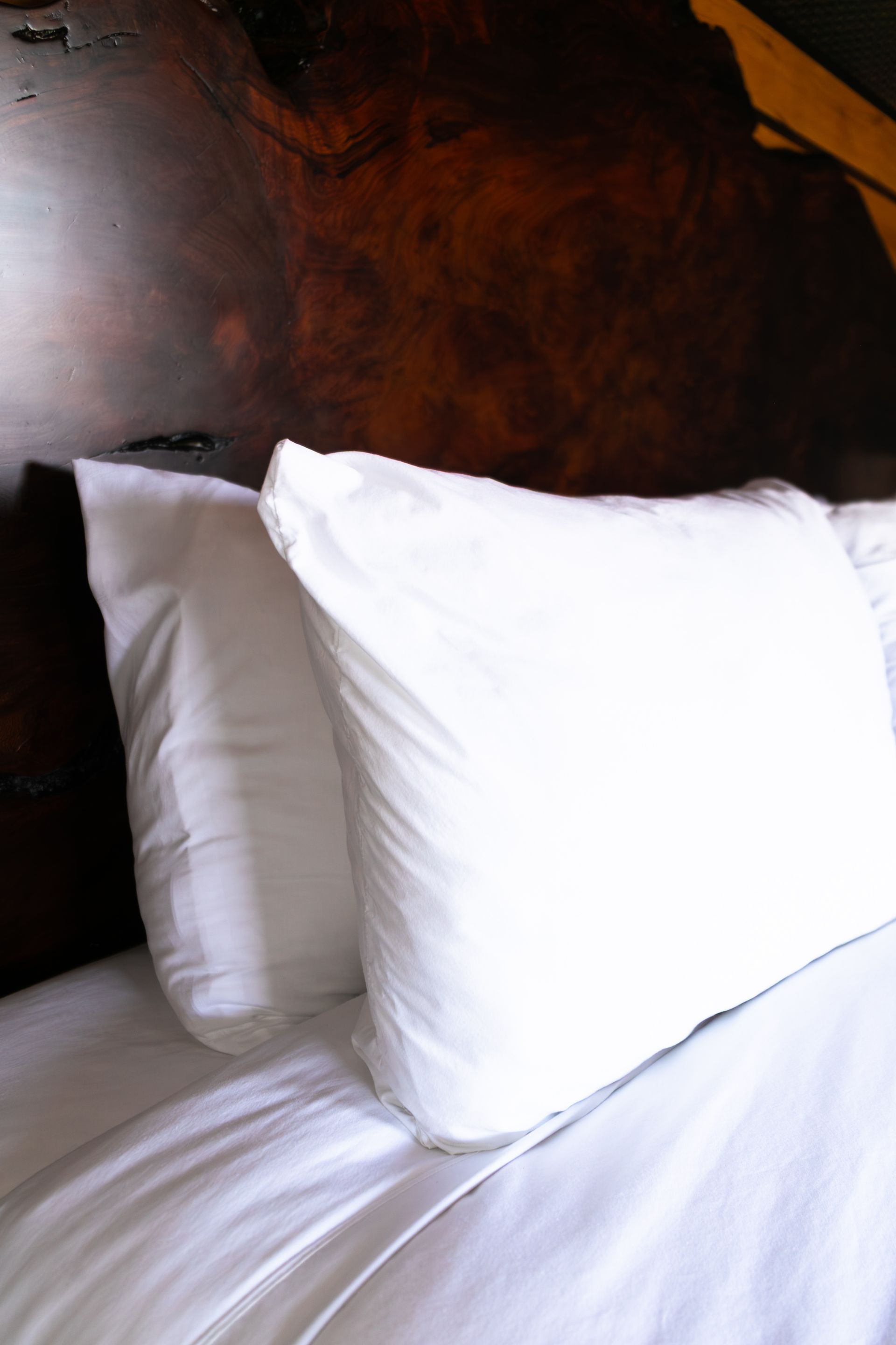 White pillows and bedding on a bed against a dark wooden headboard