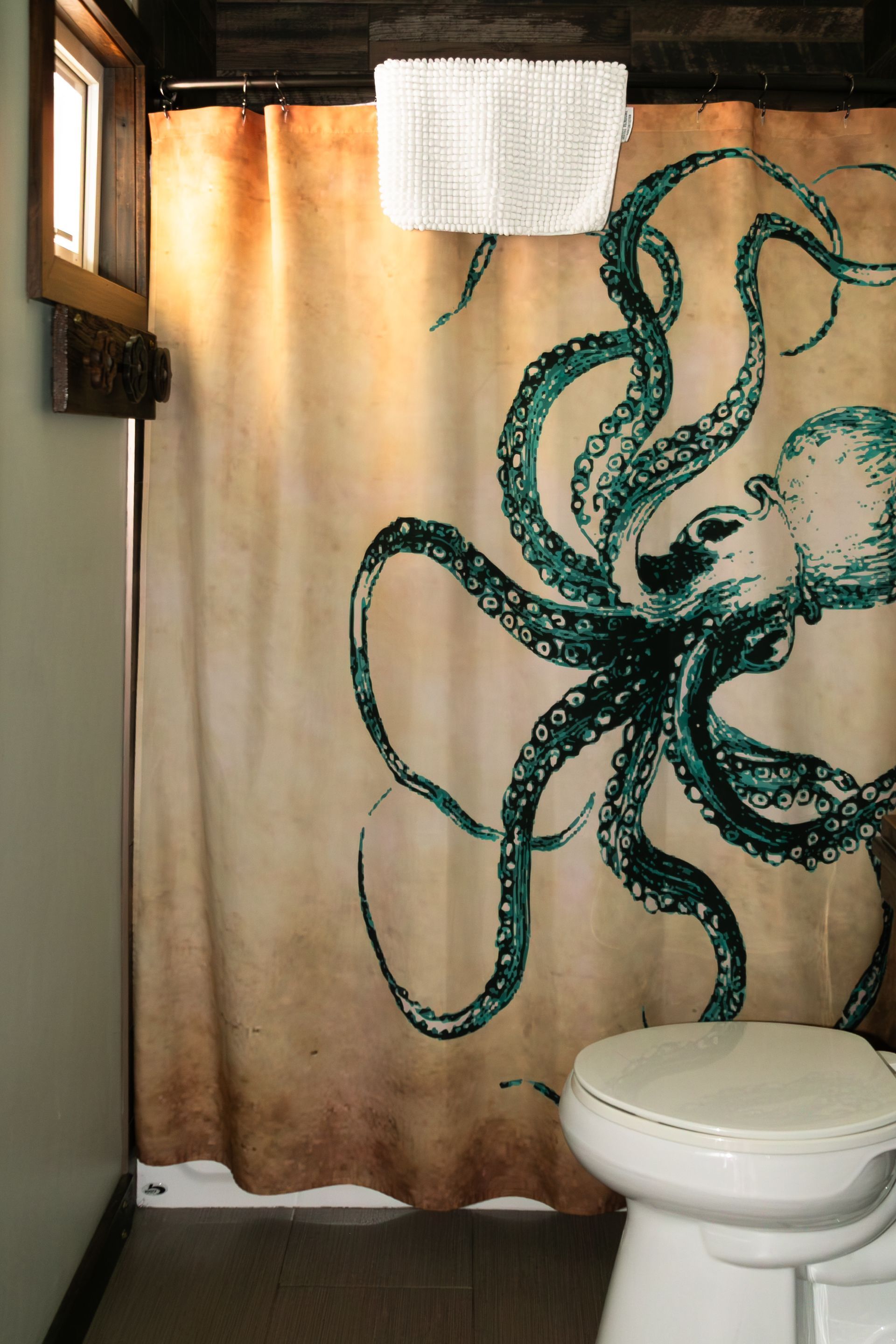 Bathroom shower curtain with a green octopus design and a white toilet in the foreground
