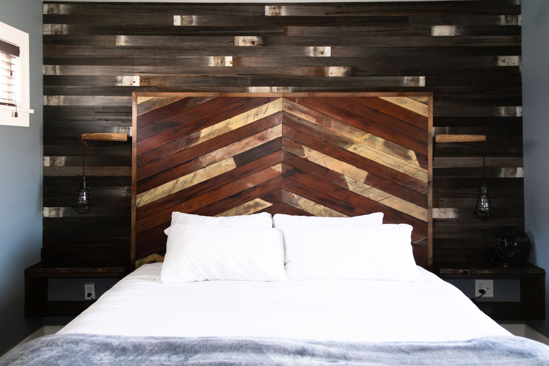 Modern bed with white bedding and a striped wood headboard against a dark wall