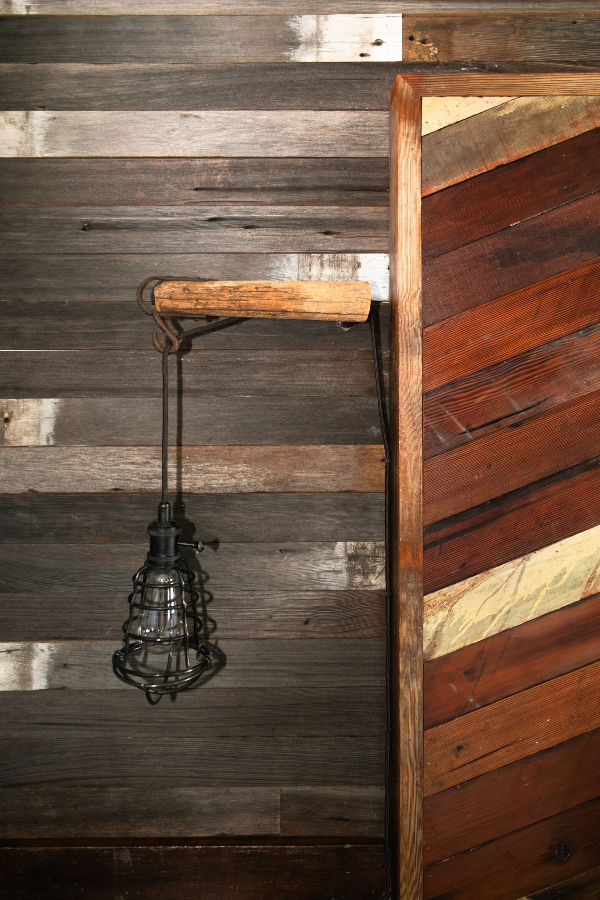 Rustic wooden wall with a hanging lantern and a partially open wooden door.