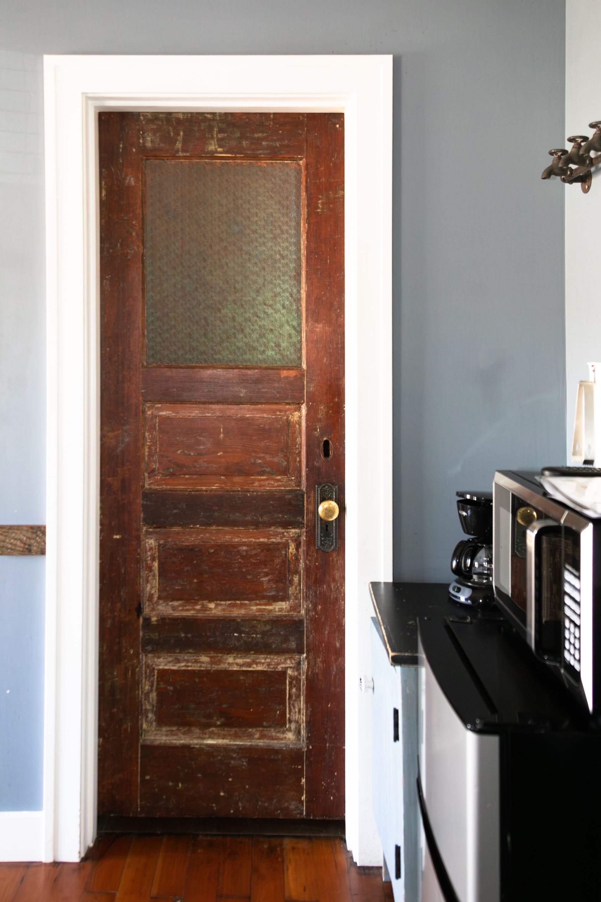 Weathered wooden door with frosted glass panel in a light blue room