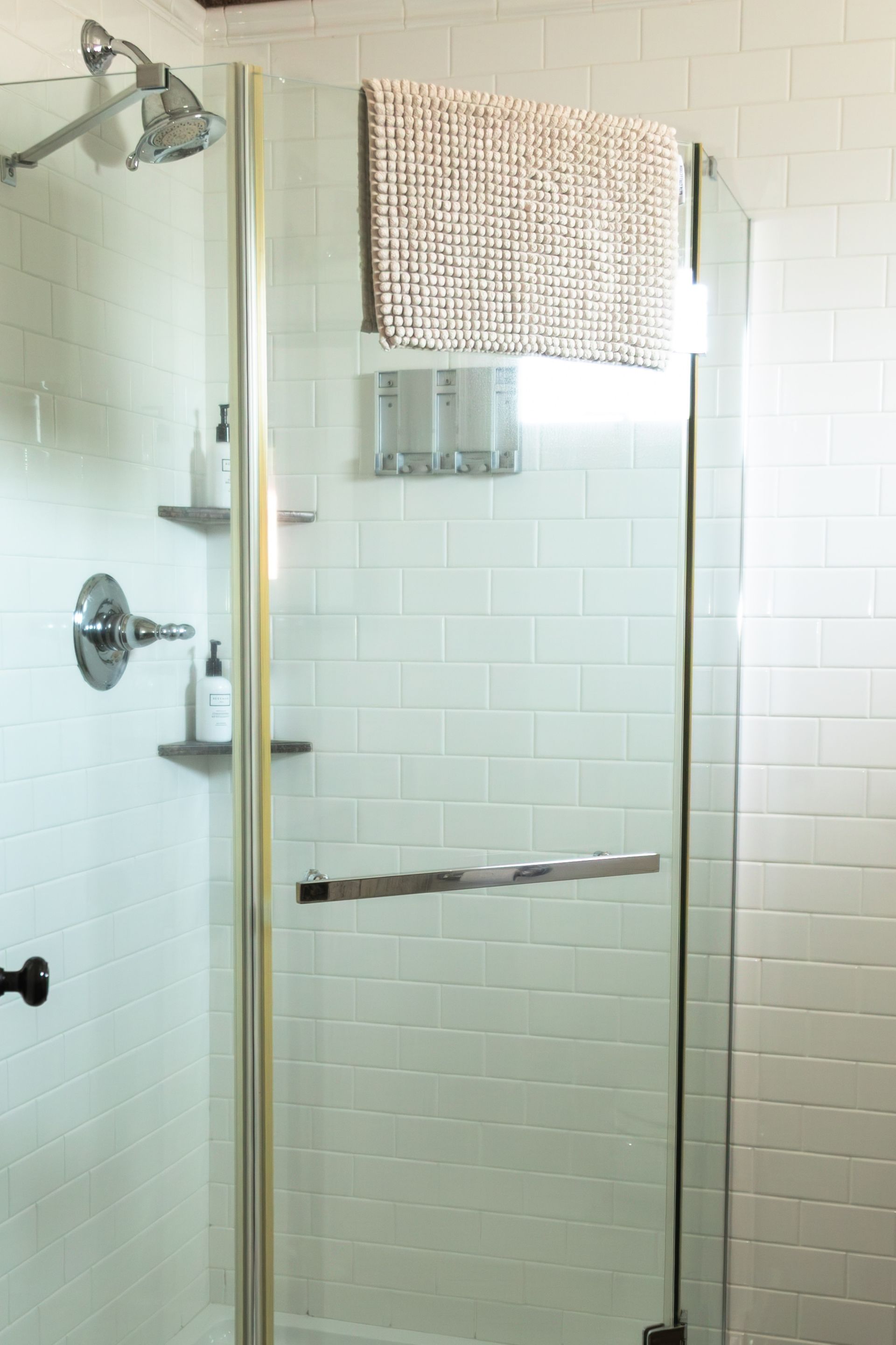 Glass shower stall with chrome fixtures and a patterned towel hanging over the door