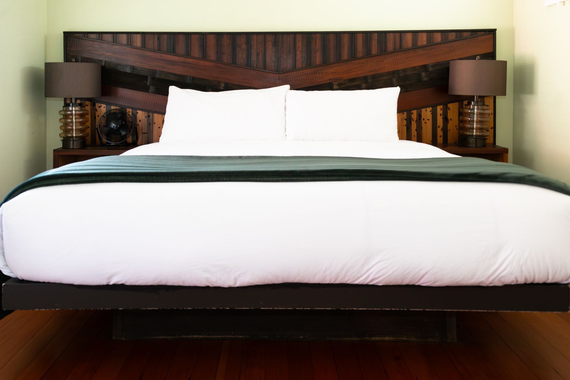 Large bed with white bedding and pillows in a modern bedroom with a dark wooden headboard