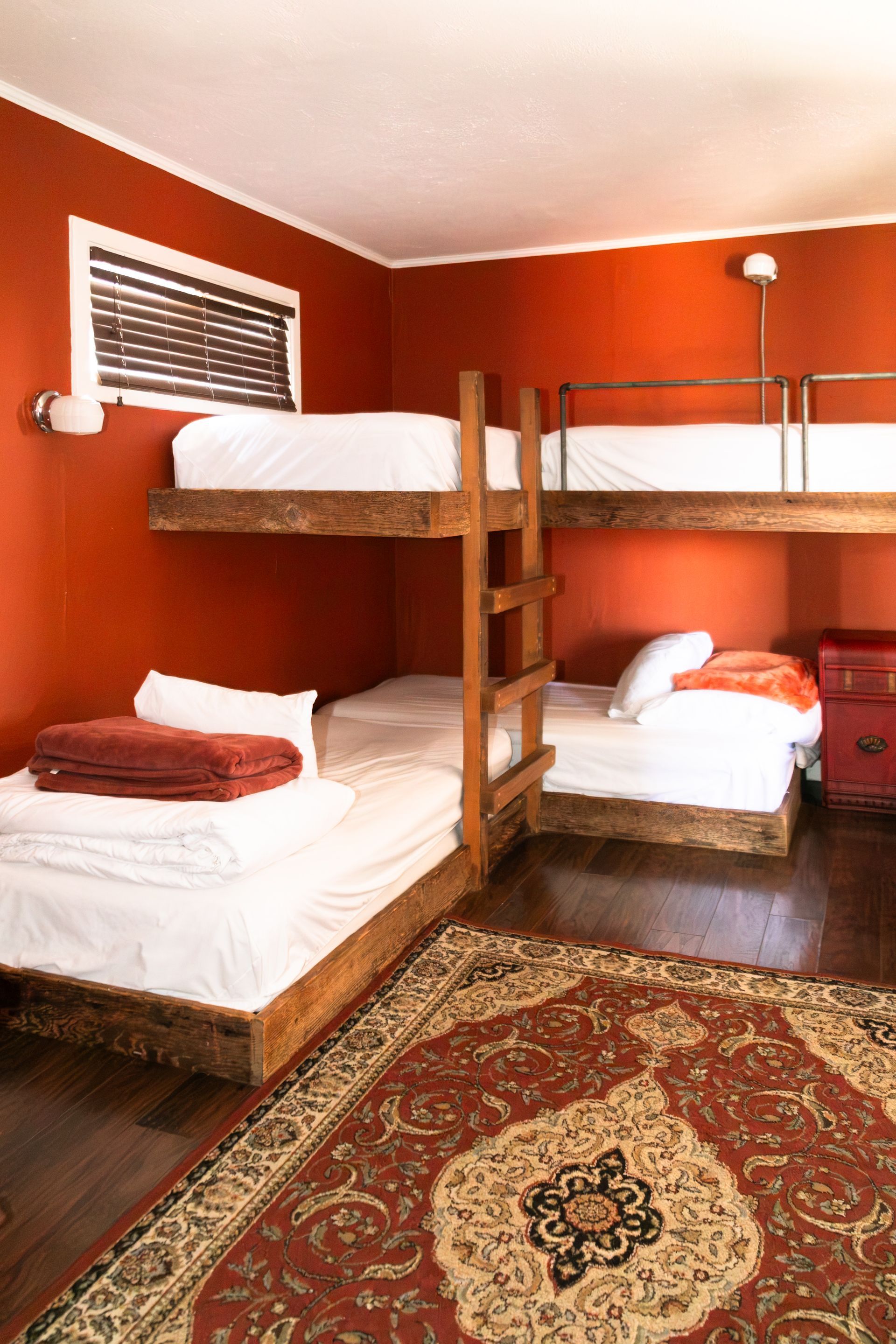Dorm room with orange walls, four bunk beds, and a patterned rug on the floor
