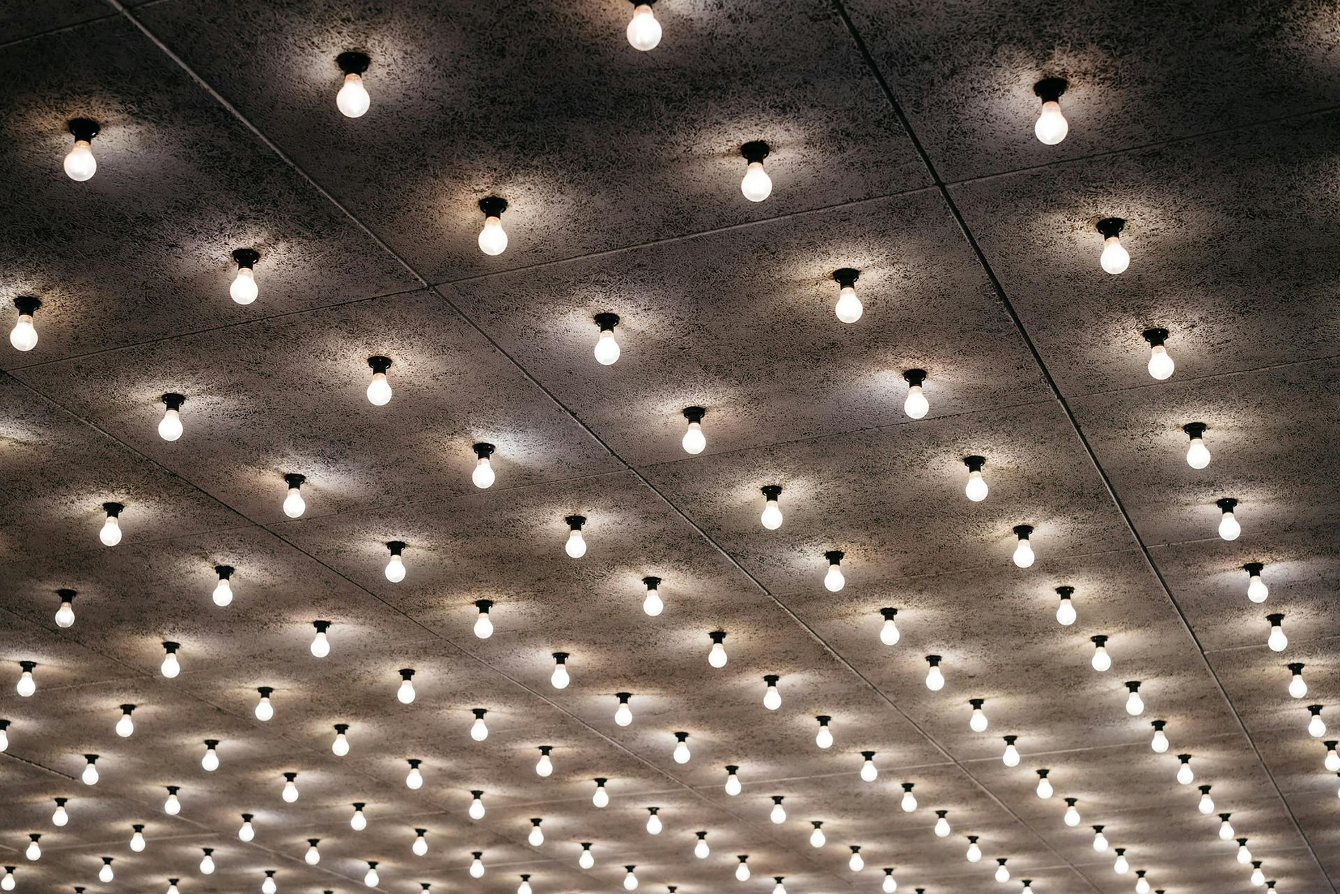 Ceiling covered with numerous lit light bulbs, casting circular light patterns.