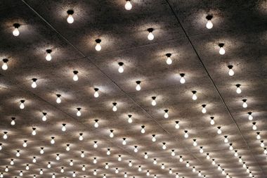 Ceiling covered with numerous lit light bulbs, casting circular light patterns.