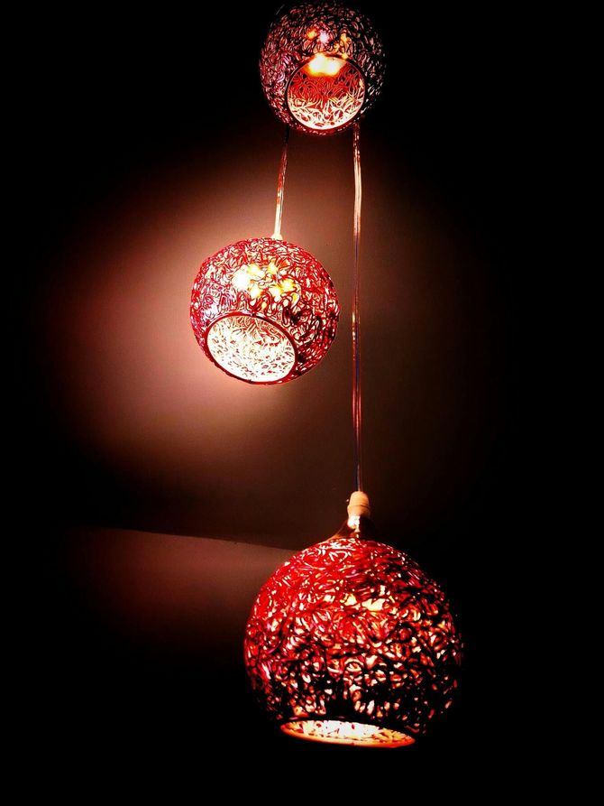 Three red spherical pendant lights hanging from the ceiling, casting a warm glow in a dark space.