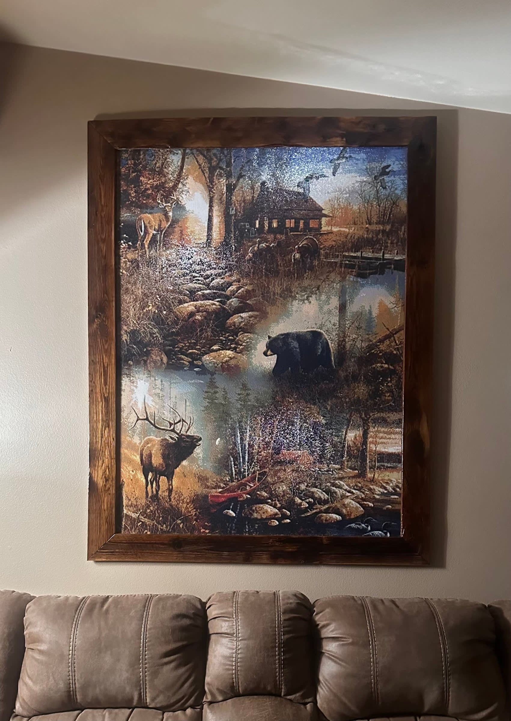 Large framed abstract landscape painting above a brown leather sofa in a beige living room