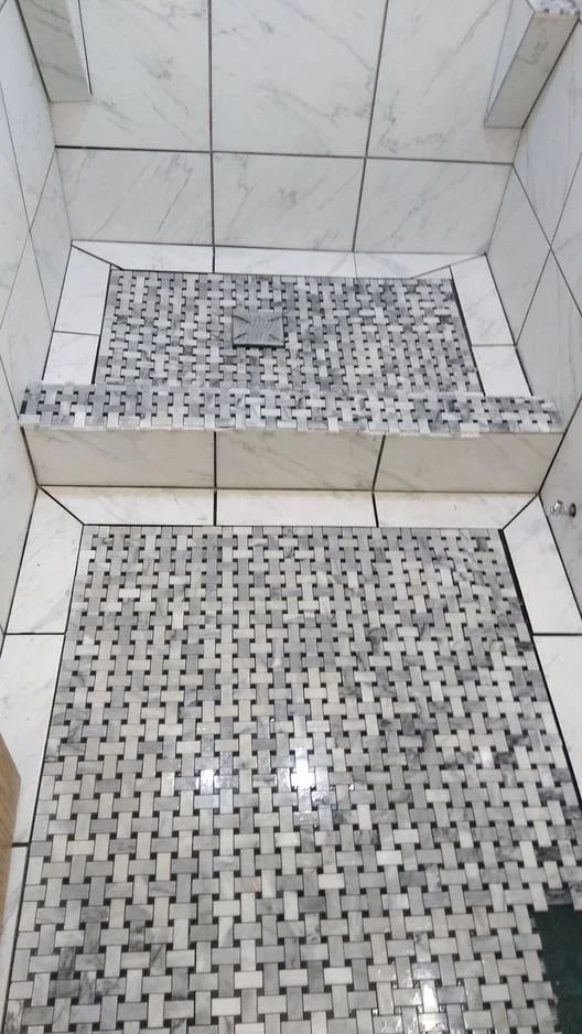 Tiled shower with a small step and mosaic floor drain area