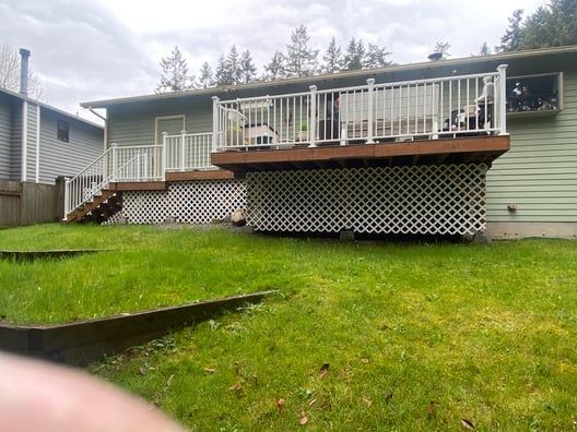 Backyard deck with white railing above a grassy yard and lattice skirting