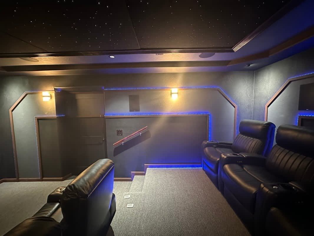 Dim home theater lounge with black leather recliners and blue LED accent lighting