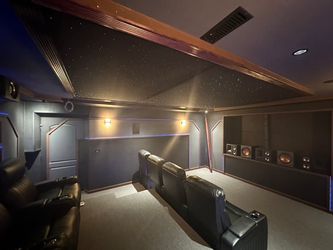 Home theater room with leather recliners, wall speakers, and starry ceiling lighting