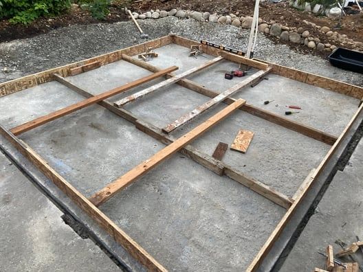 Concrete foundation with wooden formwork frames on a construction site.