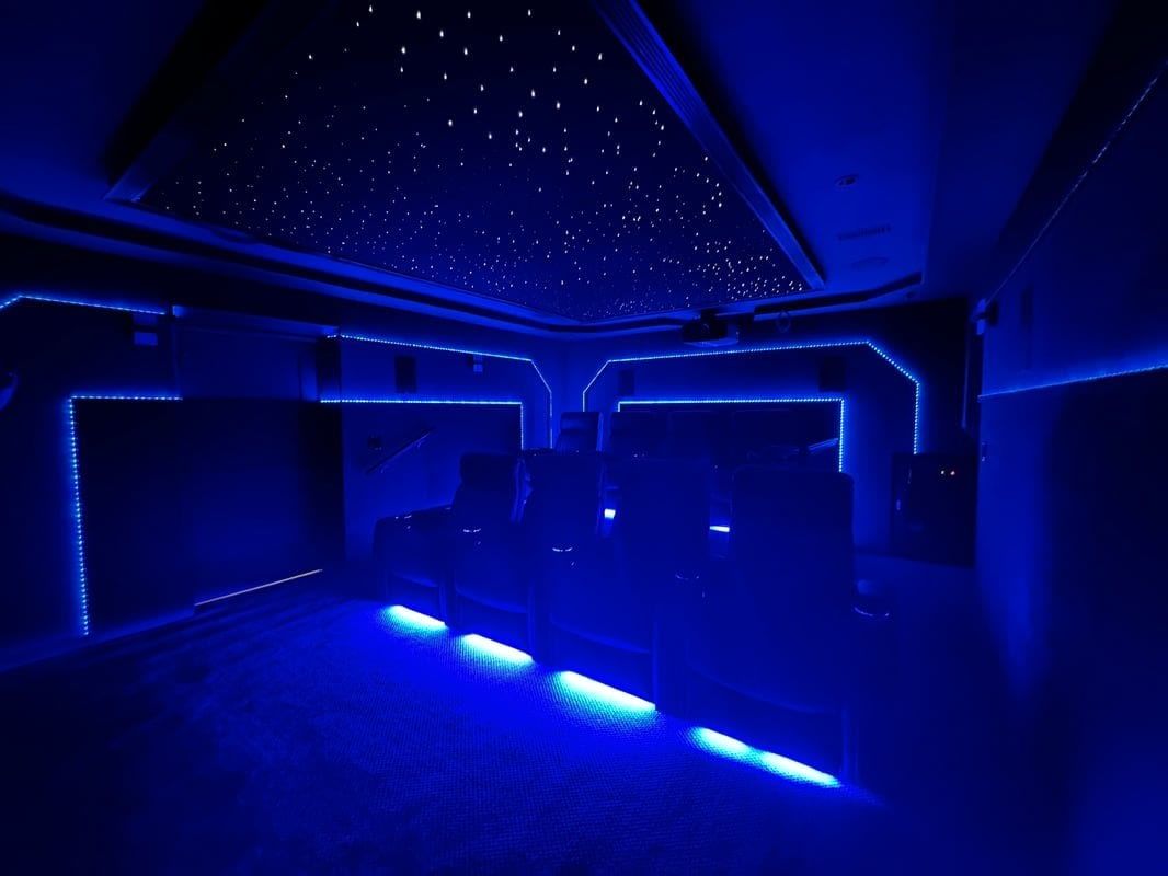 Dark room with blue LED lighting, starry ceiling, and upholstered seating underneath.
