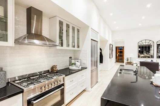 Bright modern kitchen with stainless steel stove, white cabinets, and a dark island counter