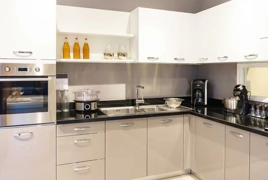 Modern kitchen with white cabinets, black countertops, built-in oven, sink, and countertop appliances