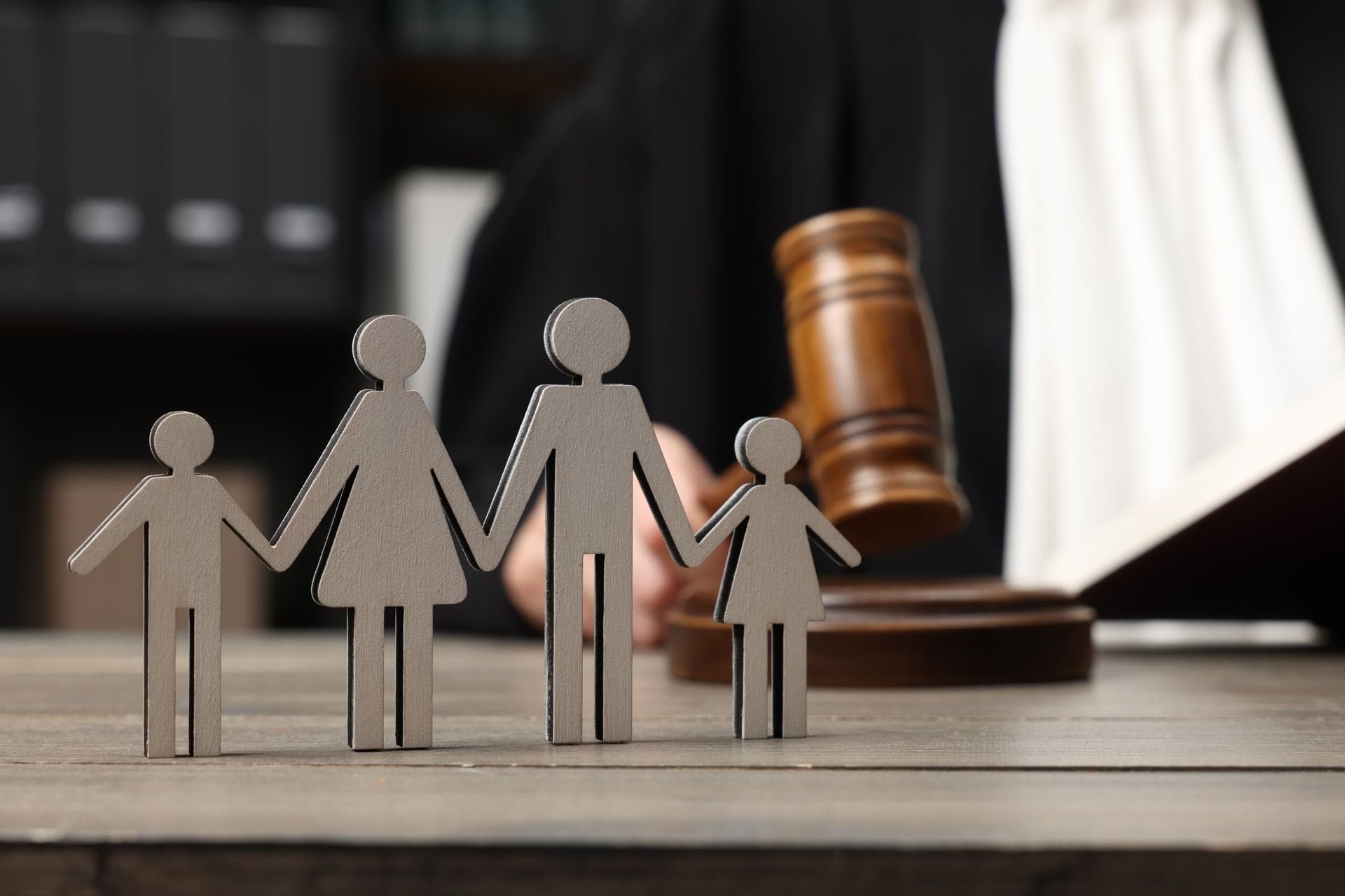 A Wooden Family Is Sitting on A Wooden Table Next to A Judge 's Gavel  — Linda Emery & Associates In Gosford, NSW