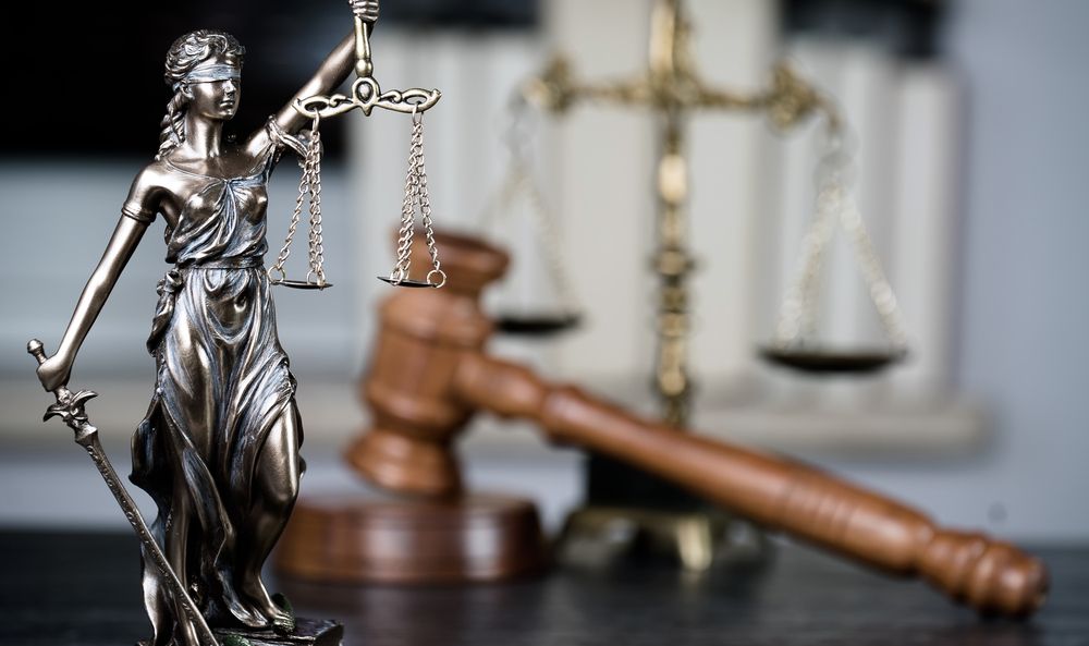 A Statue of Lady Justice Holding Scales of Justice and A Gavel on A Table — Linda Emery & Associates In Gosford, NSW