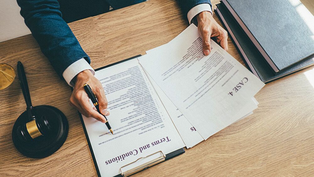 A Man Is Signing a Document on A Clipboard with A Pen — Linda Emery & Associates In Gosford, NSW