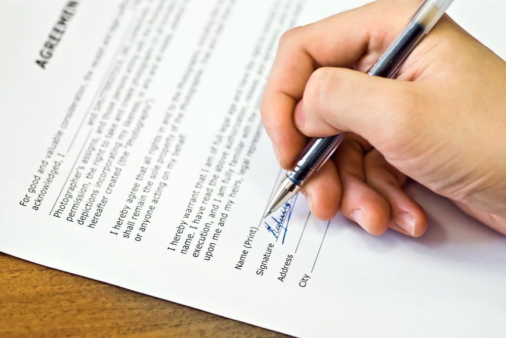 A Person Is Signing an Agreement with A Pen — Linda Emery & Associates In Gosford, NSW