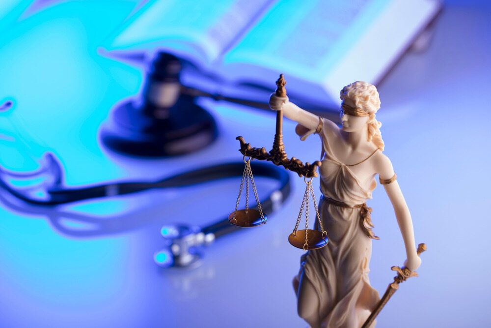 A Statue of Justice Holding Scales of Justice Next to A Stethoscope and A Judge 's Gavel — Linda Emery & Associates In Gosford, NSW