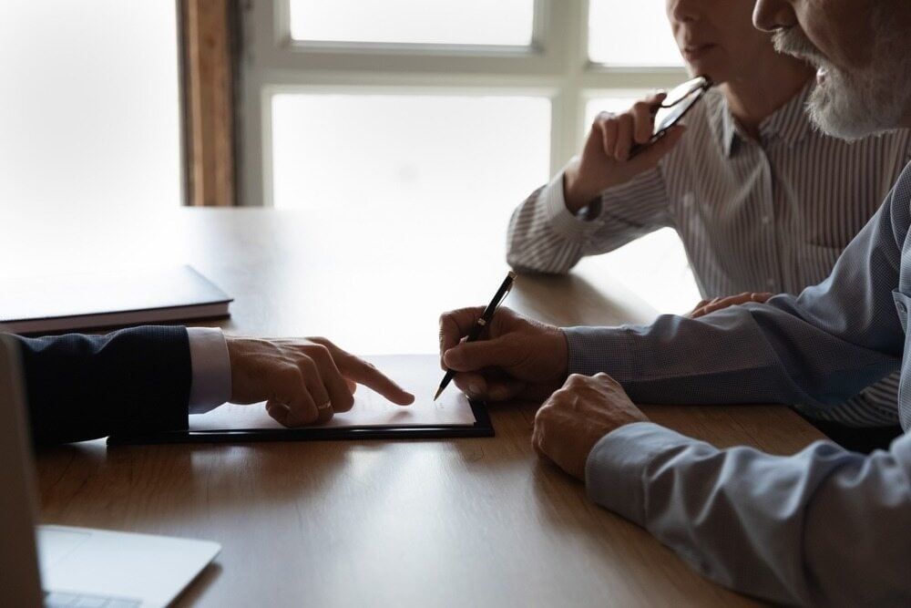 Two Men Are Sitting at A Table Looking at A Tablet — Linda Emery & Associates In Gosford, NSW