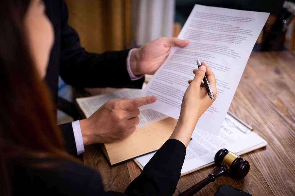 A Man and A Woman Are Sitting at A Table Looking at A Piece of Paper — Linda Emery & Associates In Gosford, NSW