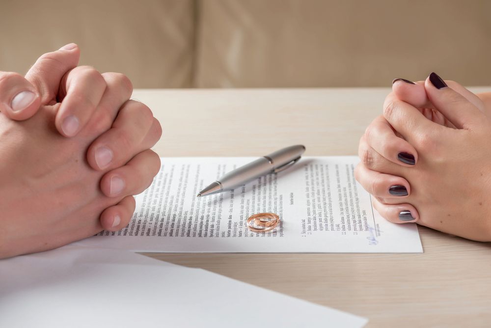 Hands of a Couple, Wedding Ring, and Pen on a Table — Linda Emery & Associates In Gosford, NSW