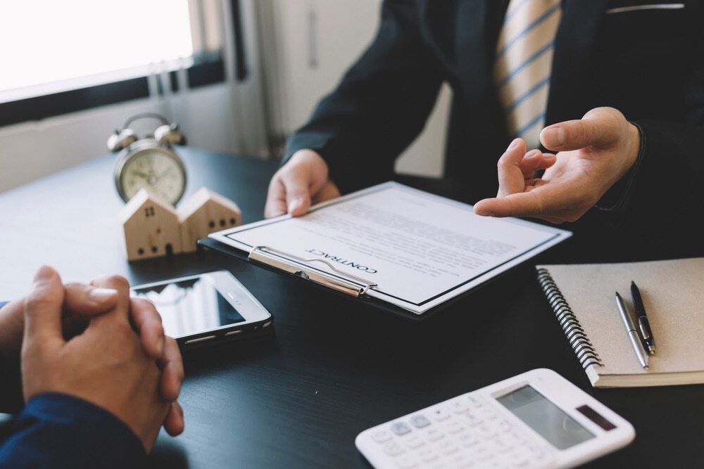 Two Men Are Sitting at A Table Looking at A Piece of Paper — Linda Emery & Associates In Gosford, NSW