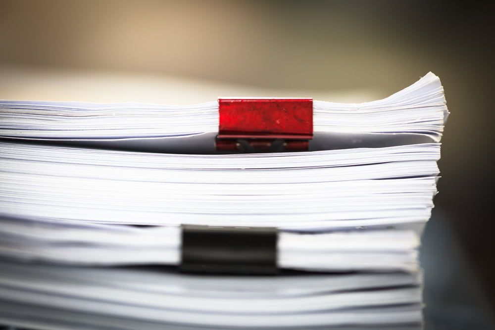 A Stack of Paper with A Red Clip on Top of It — Linda Emery & Associates In Gosford, NSW