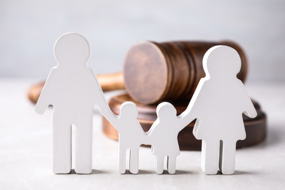 A Wooden Family Holding Hands in Front of A Judge 's Gavel — Linda Emery & Associates In Gosford, NSW