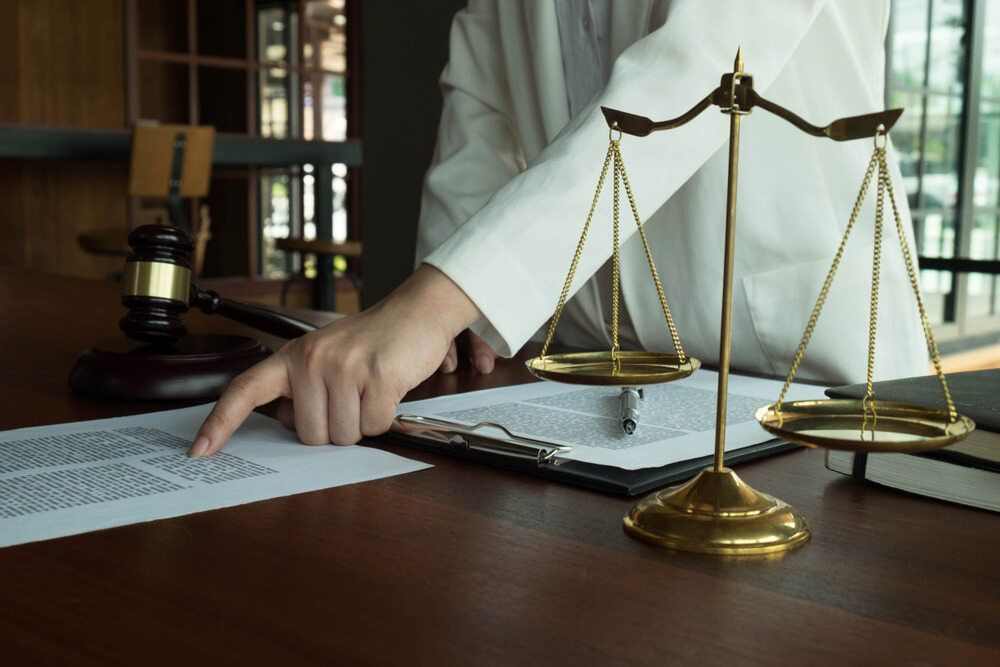 A Judge Is Sitting at A Table with Scales of Justice and A Gavel — Linda Emery & Associates In Erina, NSW