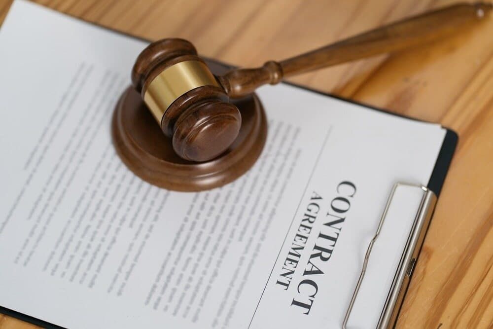 A Judge 's Gavel Is Sitting on Top of A Contract Agreement on A Clipboard — Linda Emery & Associates In Gosford, NSW