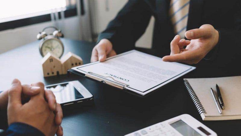 Two Men Are Sitting at A Table Looking at A Piece of Paper — Linda Emery & Associates In Gosford, NSW