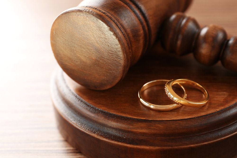 Two Wedding Rings Are Sitting on Top of A Wooden Gavel — Linda Emery & Associates In Gosford, NSW