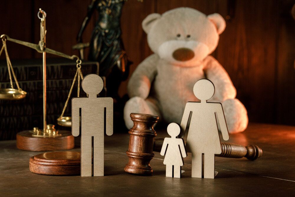 A Teddy Bear Is Sitting on A Wooden Table Next to A Judge 's Gavel and Scales of Justice — Linda Emery & Associates In Gosford, NSW