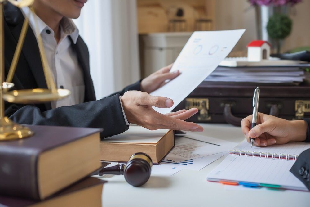 A Man Is Giving a Piece of Paper to A Woman Who Is Signing a Document — Linda Emery & Associates In Gosford, NSW