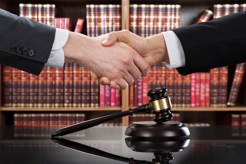 Two Men Shaking Hands in Front of A Judge 's Gavel — Linda Emery & Associates In Gosford, NSW