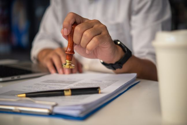 A Person Is Stamping a Document with A Wax Seal — Linda Emery & Associates In The Entrance, NSW
