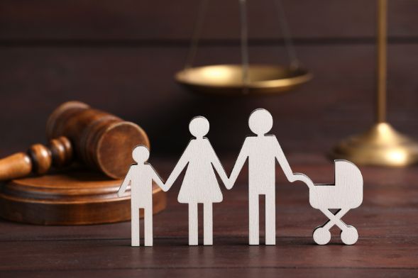 A Family Cut out Of Paper Is Standing Next to A Judge 's Gavel and Scales of Justice — Linda Emery & Associates In Wyoming, NSW