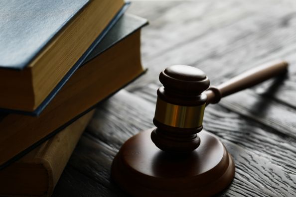 A Judge 's Gavel Is Sitting on A Wooden Table Next to A Stack of Books — Linda Emery & Associates In Gosford, NSW