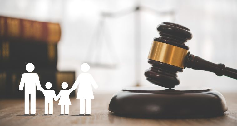 A Family Is Standing Next to A Judge 's Gavel on A Wooden Table — Linda Emery & Associates In Morisset, NSW